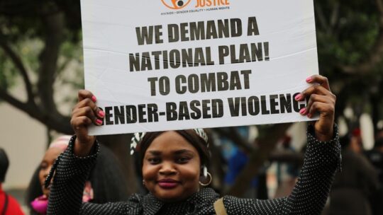 Image of a woman holding a placard, which reads: We demand a national plan to combat Gender-Based Violence. Photo credit: Sonke Gender Justice